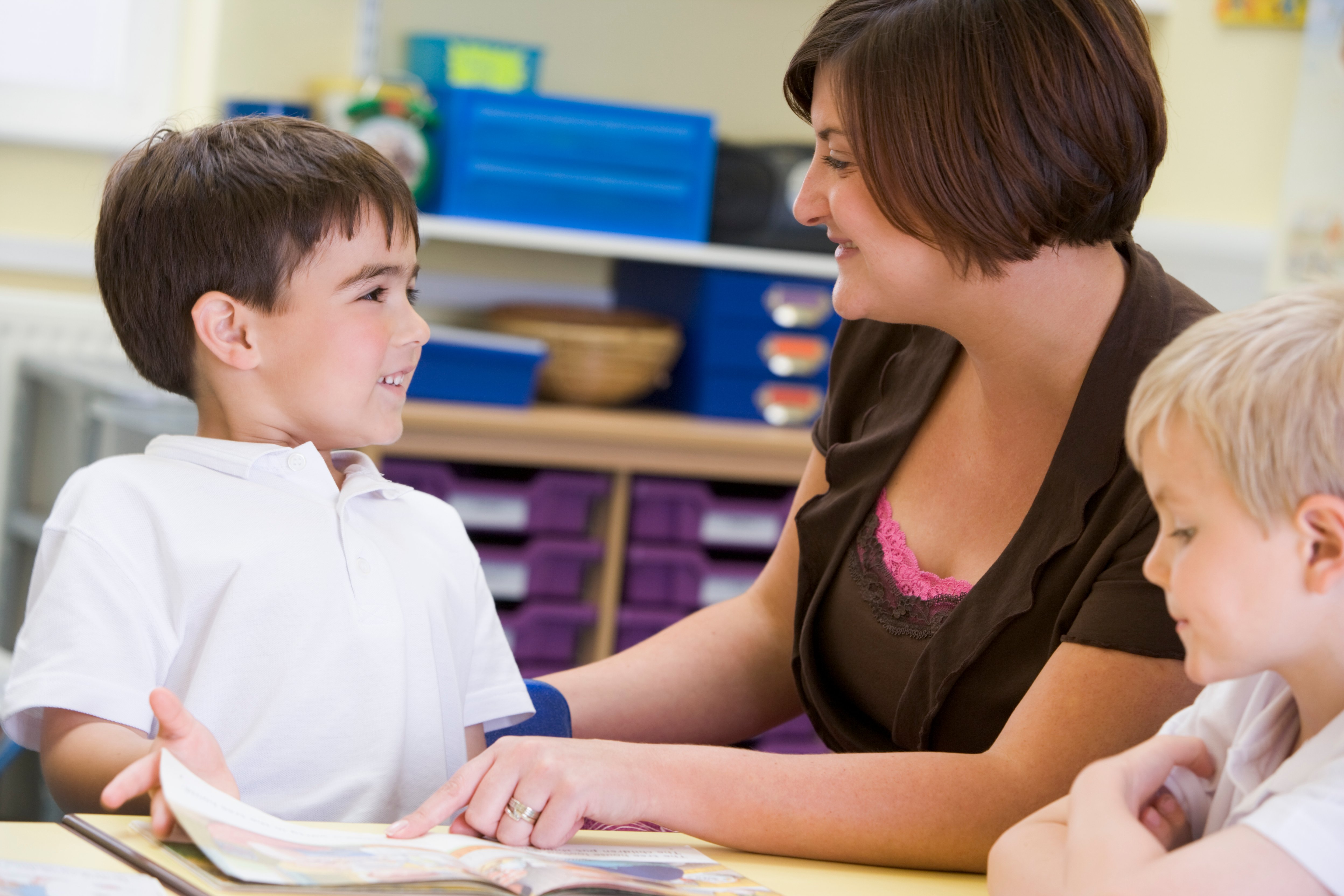 A schoolboy and his teacher reading in a primary class BFTsw0ASs