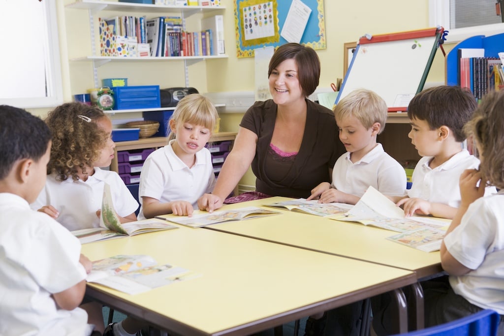 Schoolchildren and their teacher reading in primary class BttePOAABj