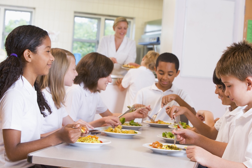 Schoolchildren enjoying their lunch in a school cafeteria BKIrURRSj
